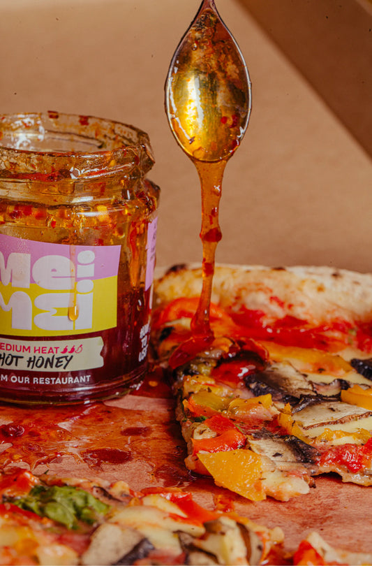 Mei Mei hot honey being drizzled onto a pizza